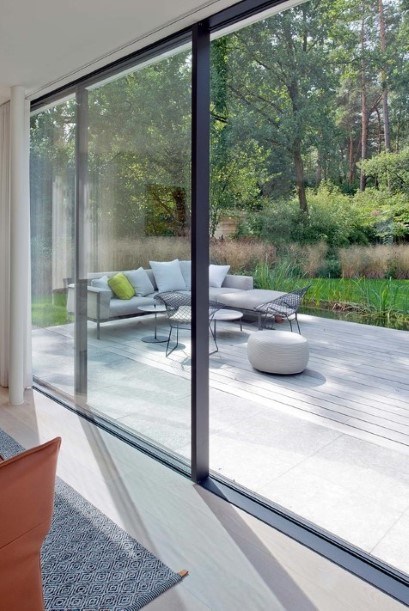 grandes fenêtres avec profilés en aluminium noir avec vue sur la terrasse et le jardin
