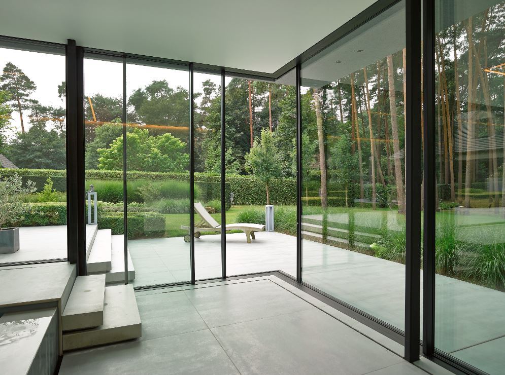 grandes fenêtres en aluminium noir avec de grandes baies vitrées donnant sur la terrasse et le jardin