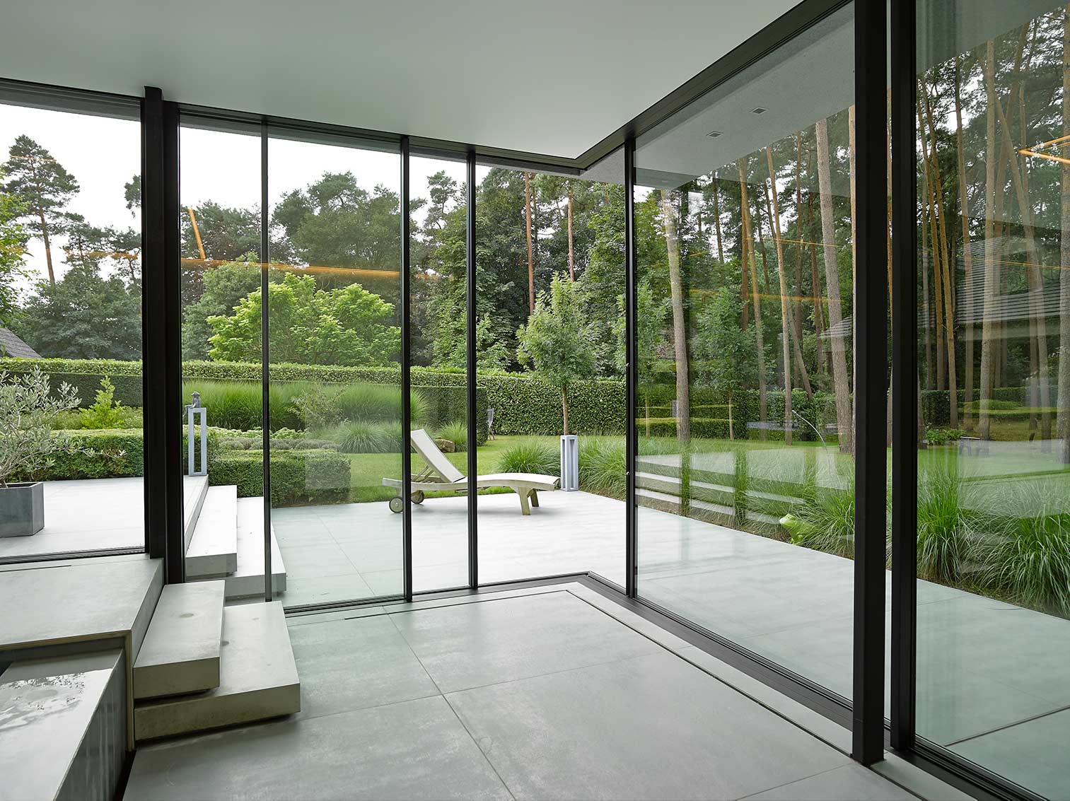 moderne villa met grote zwarte aluminium ramen met grote glaspartijen met zicht op terras en tuin