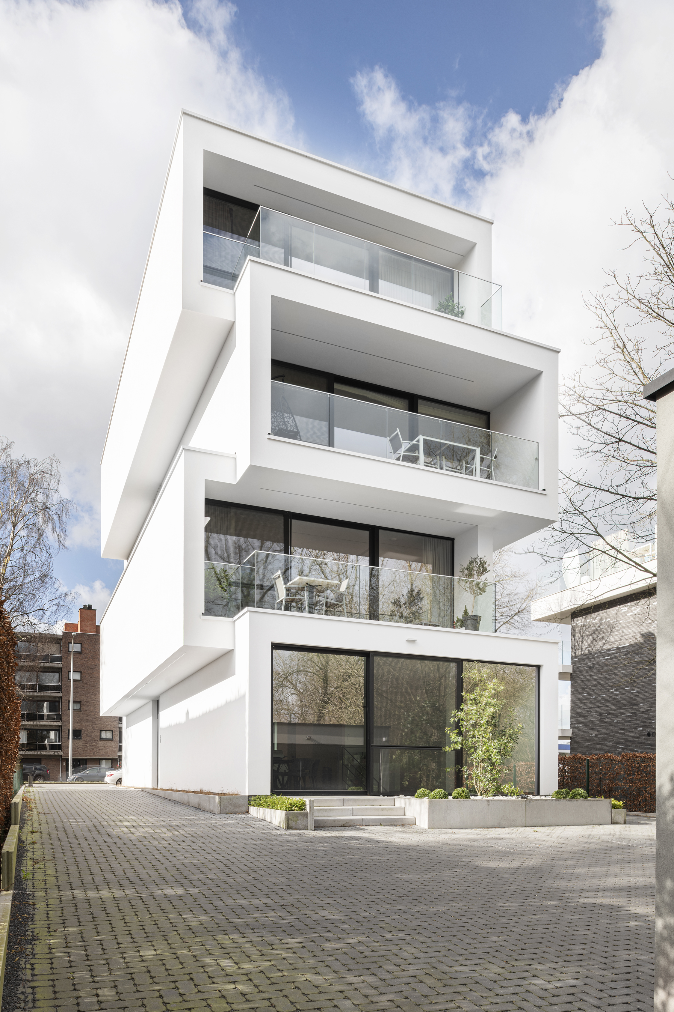 a tall residential home with white painted detail and floor to ceiling glazing. This has a modern contemporary aesthetic. 