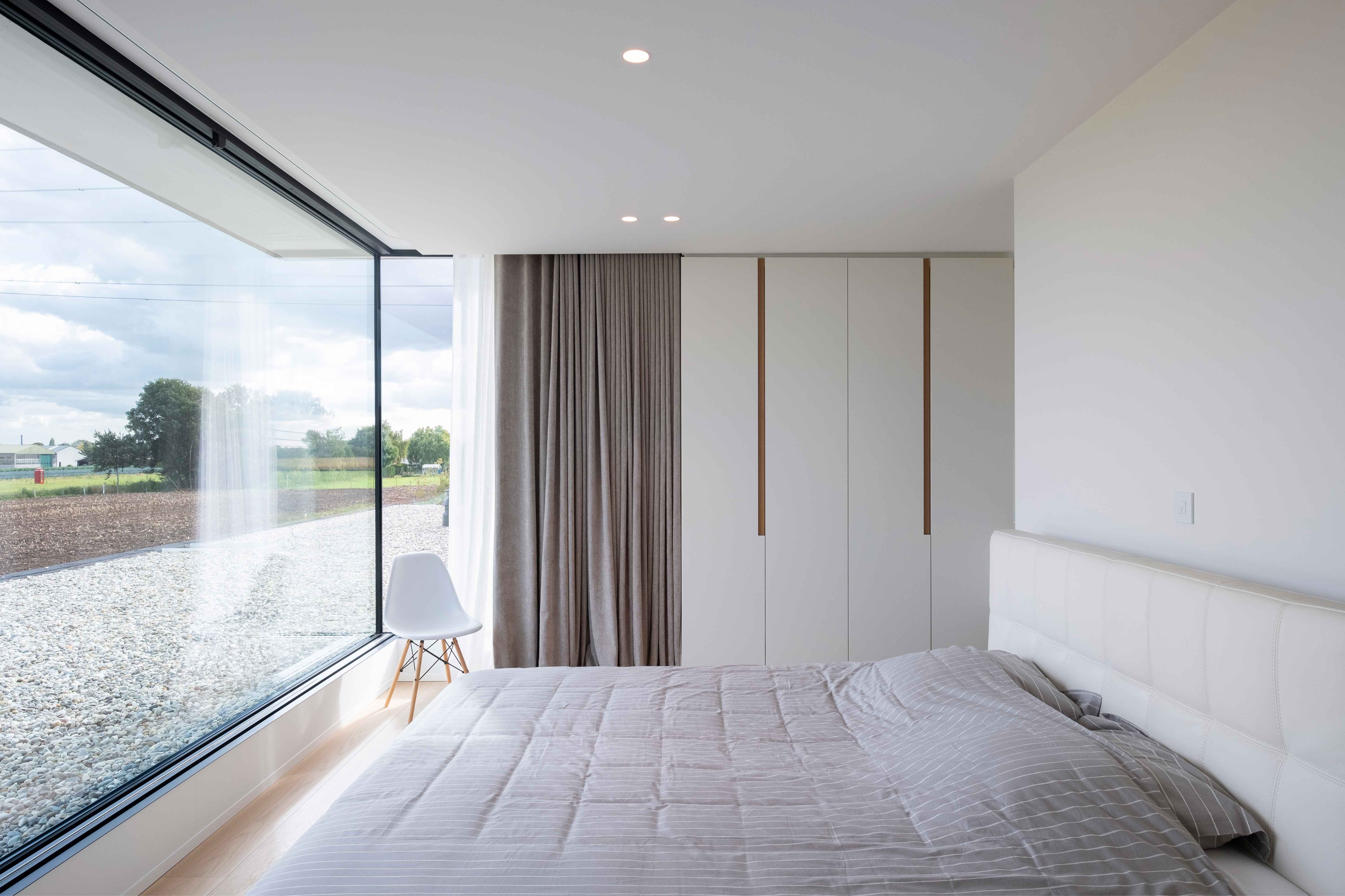 moderne witte slaapkamer met groot raam met zwarte aluminium profielen