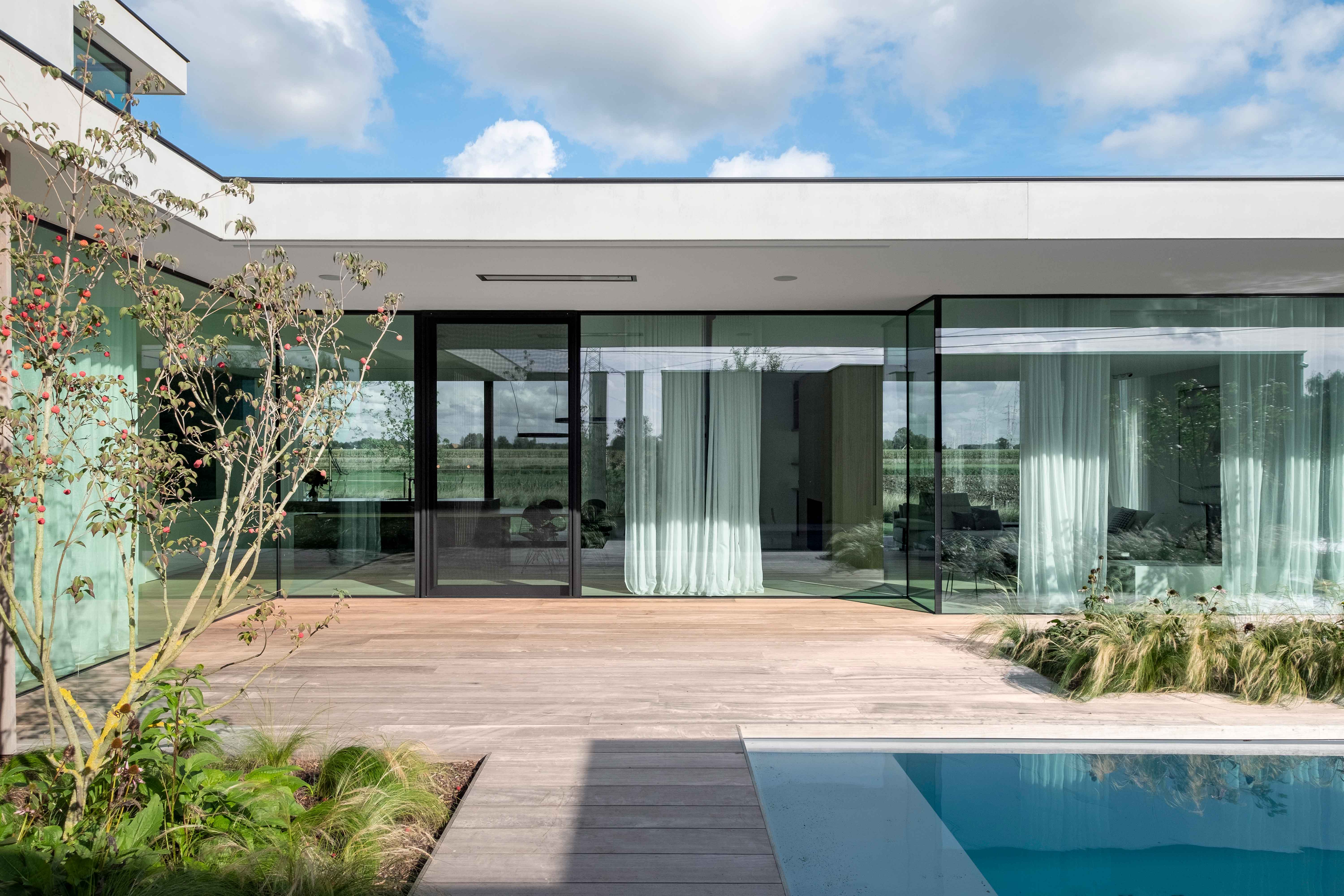 witte villa met grote ramen met zwarte aluminium profielen met zicht op zwembad